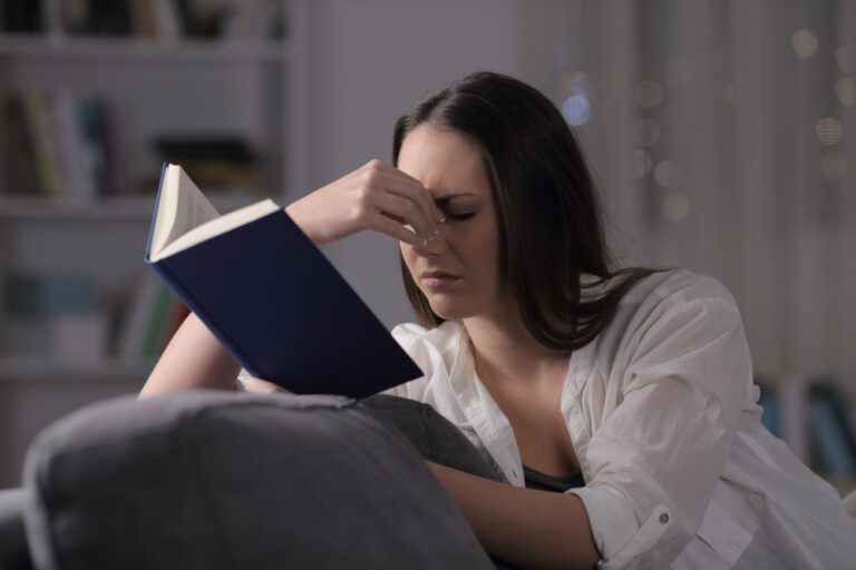 Mulher com dificuldade de ler livro.